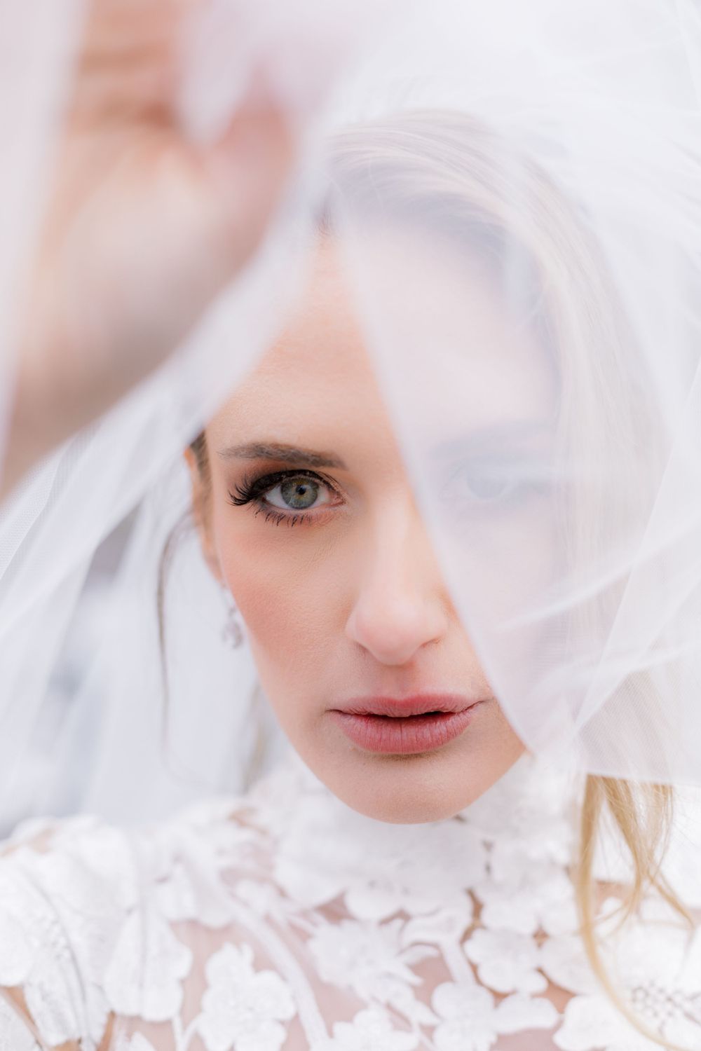 Ethereal bridal portrait with soft focus showing romantic details through a sheer veil.