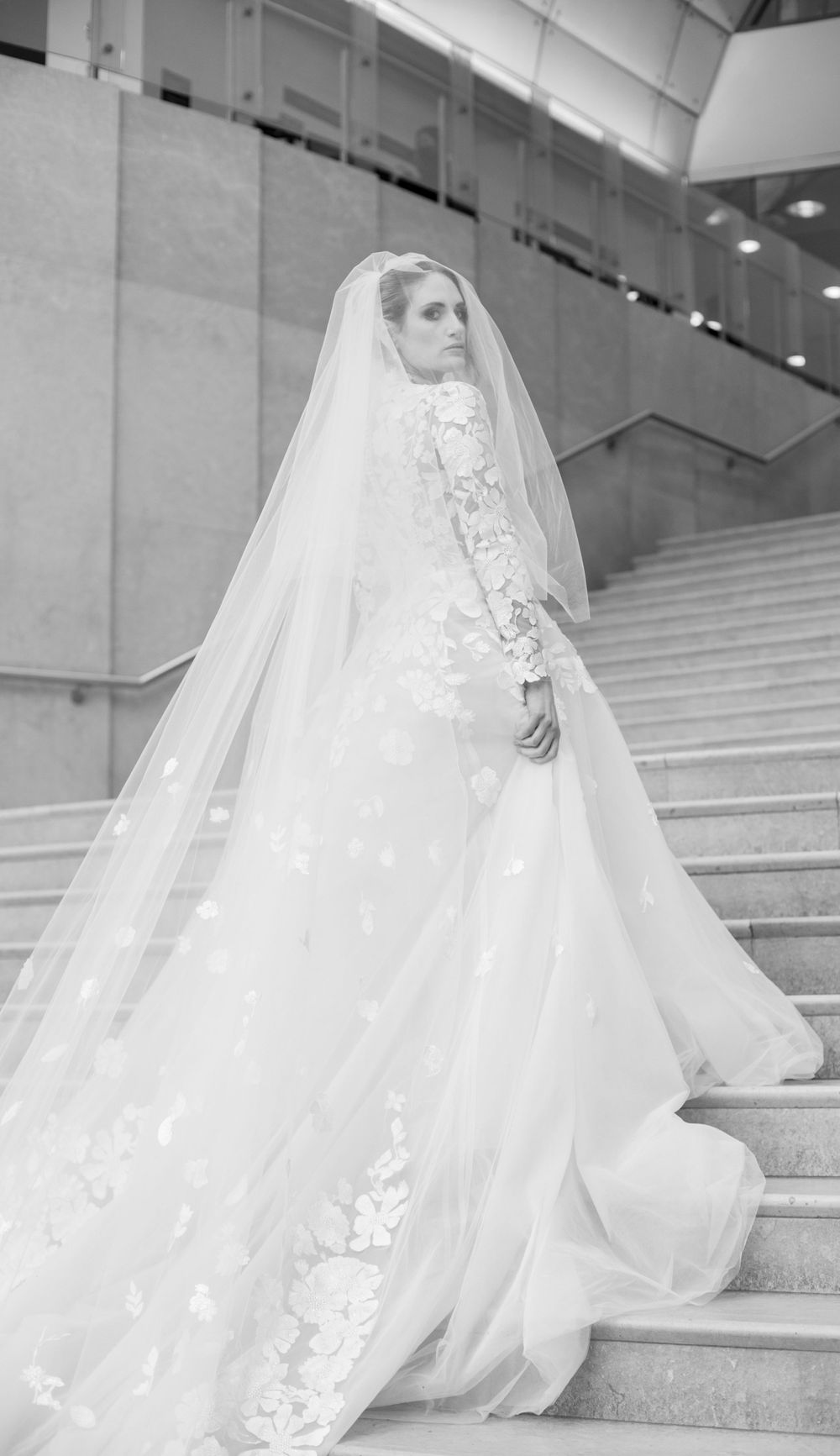 Elegant full-length bridal portrait on grand staircase showcasing lace wedding gown and flowing veil.