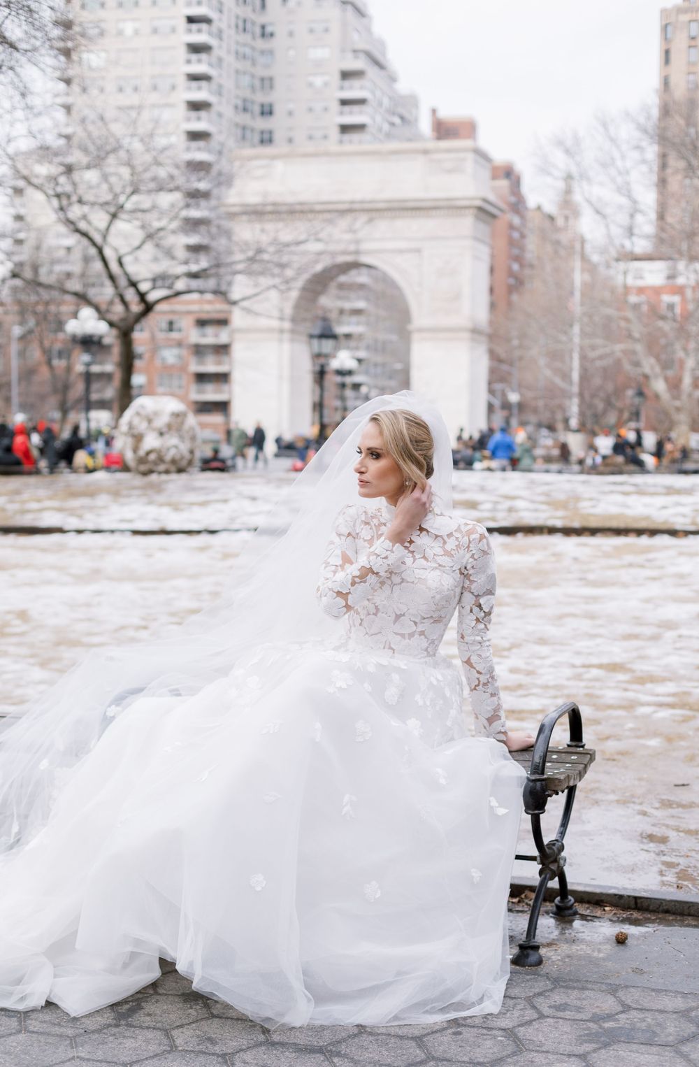 Winter bridal portrait with dramatic flowing veil against Washington Square Arch.
