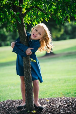 young girl smiling and posing with a tree