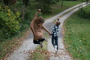 siblings on road jumping for joy