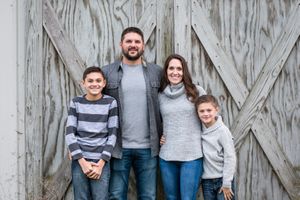 family photo with two sons in front of barn doors