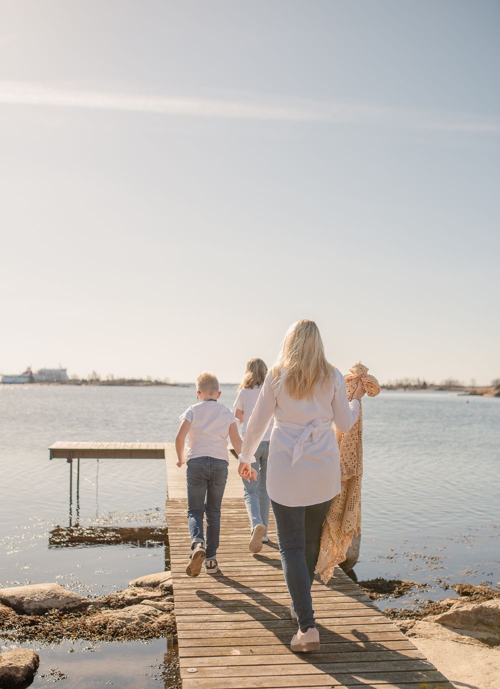 Walking along a wooden dock by the water at sunset in matching white tops and denim.