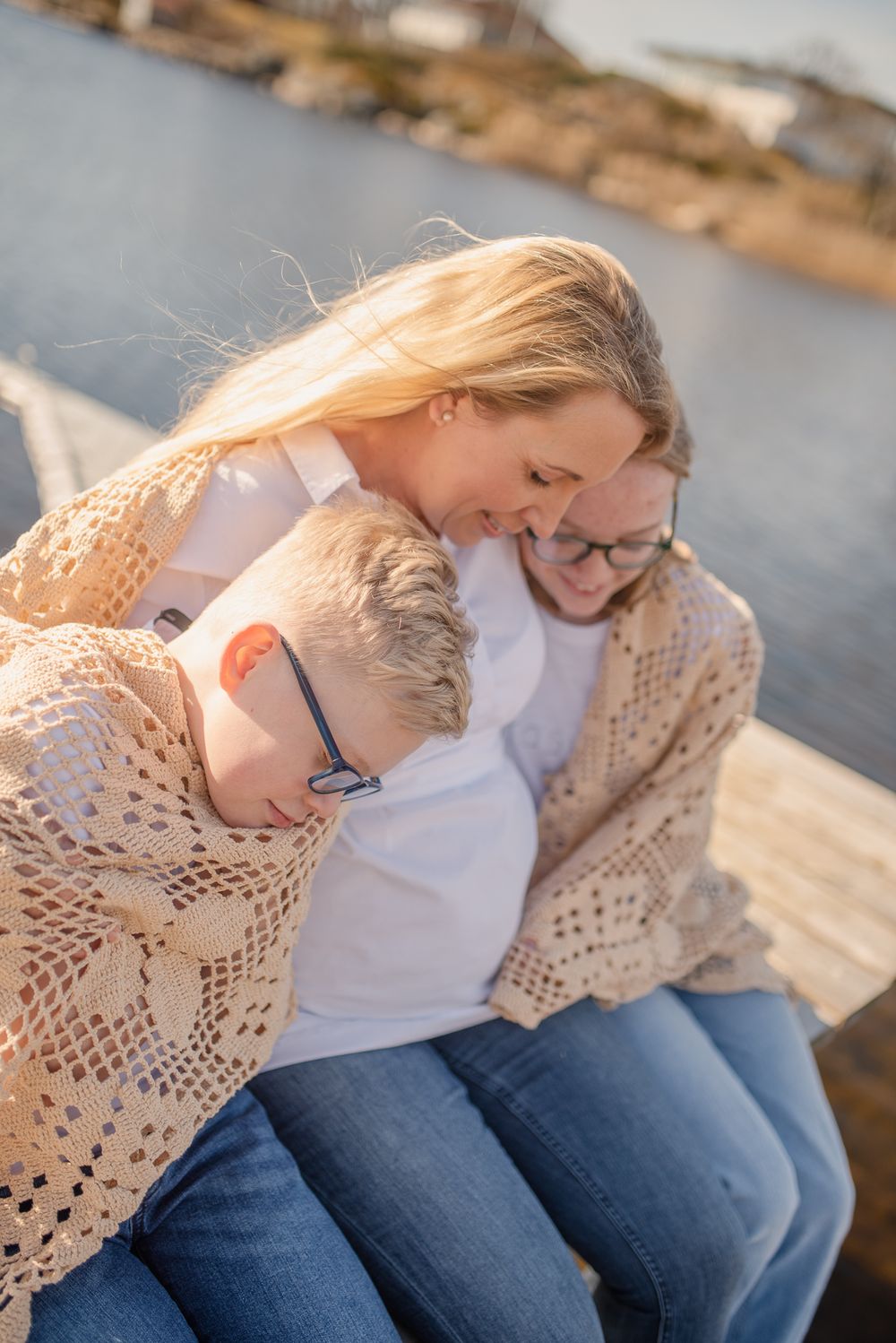 Cozy family moment on a dock wearing knit sweaters by the water at sunset.
