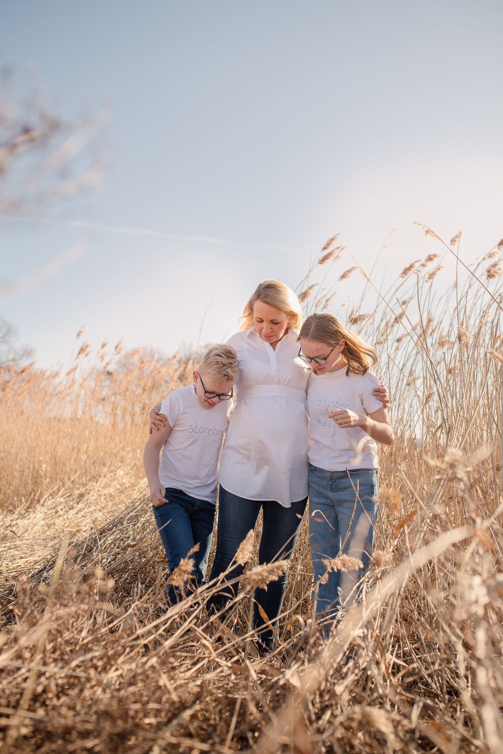 Family walking together through golden grass field at sunset.