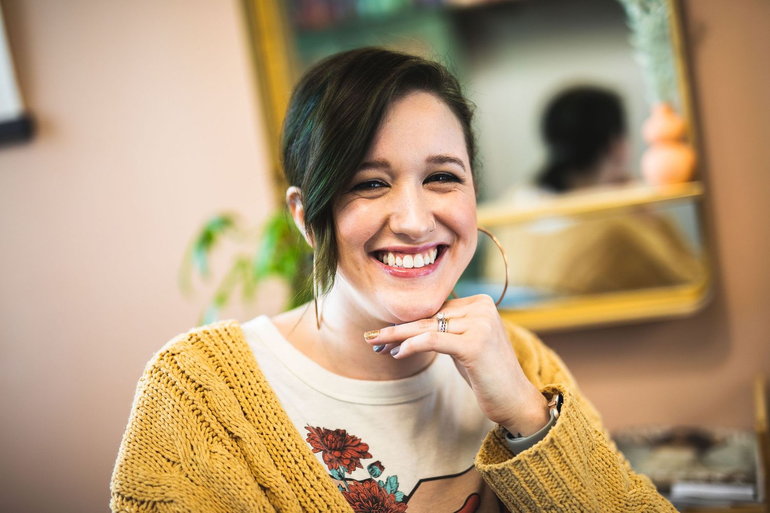 A candid portrait of someone in a yellow sweater showing genuine joy and warmth.