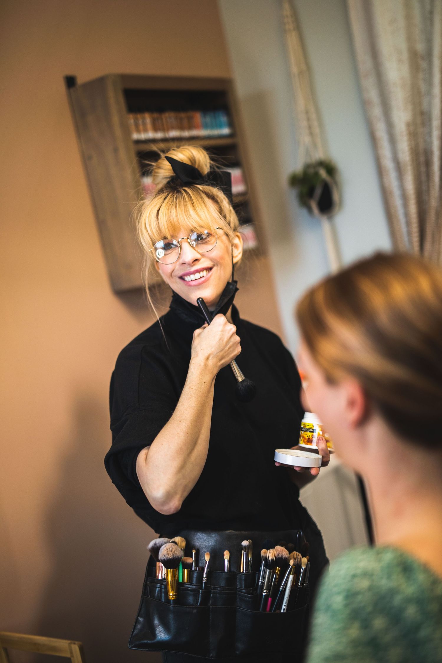 A makeup artist with professional brushes preparing for a beauty session.
