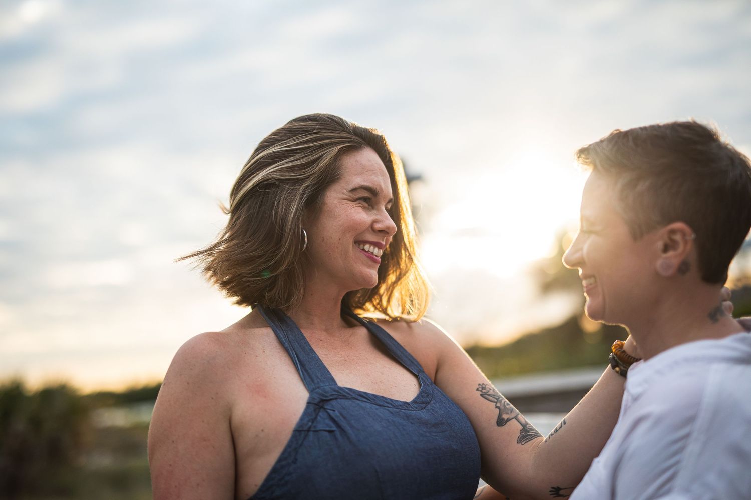 A candid moment captured between two people during golden hour on a boardwalk.