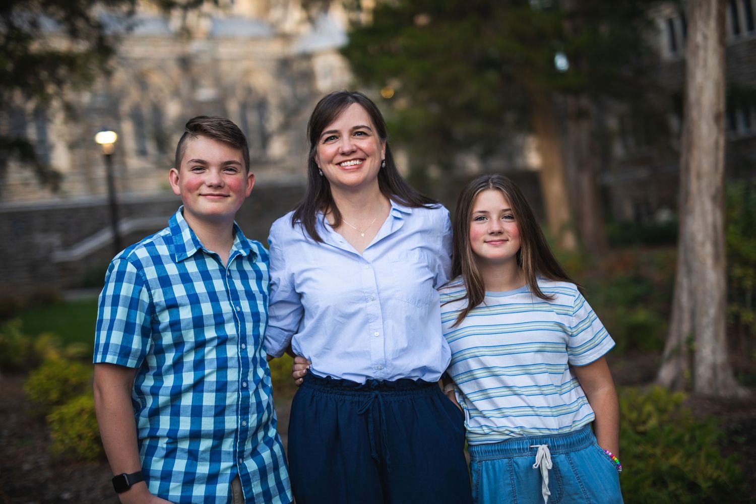 An outdoor family portrait taken at dusk with stone buildings in the background.