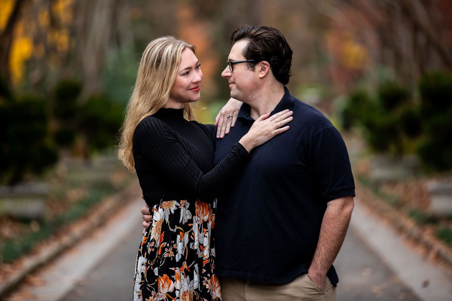 A romantic autumn engagement photo with fallen leaves in the background.