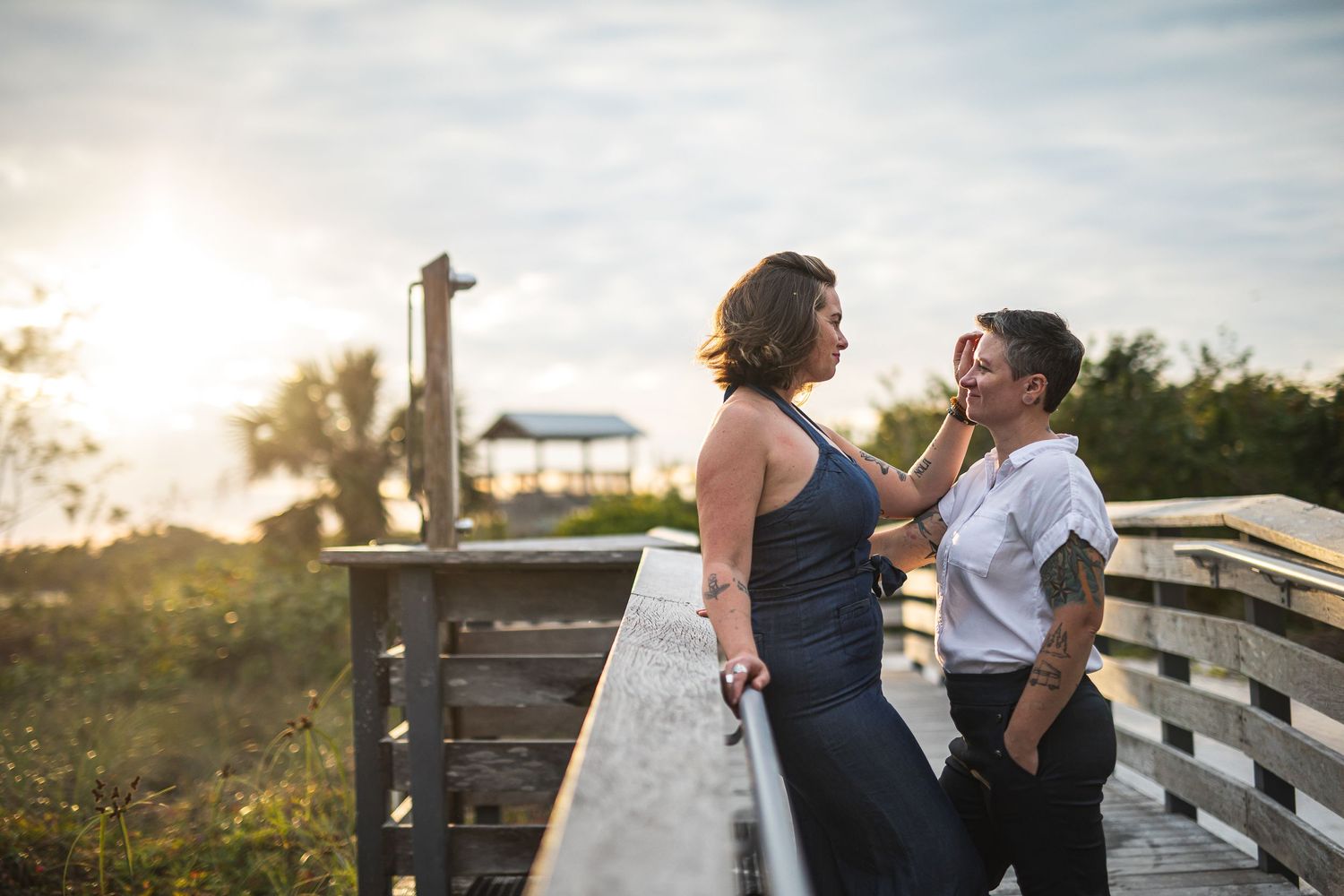 A sunset engagement photo on a wooden boardwalk with golden lighting.