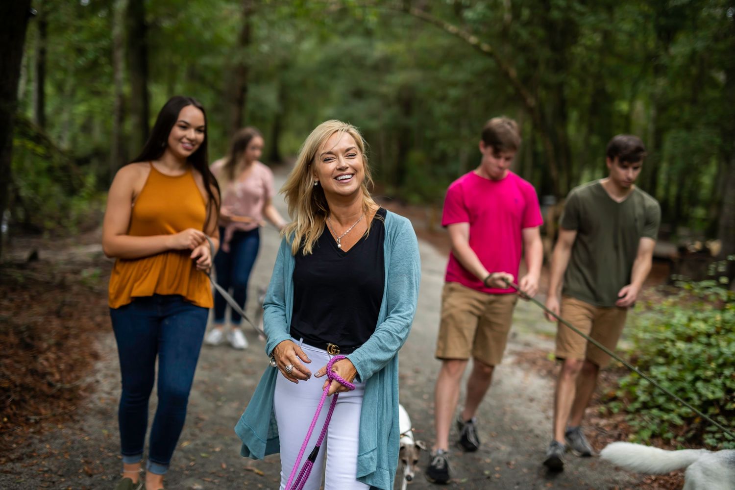 A group hiking through a wooded trail carrying walking sticks.
