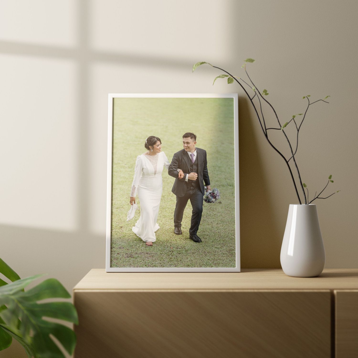 Wedding photographs displayed on shelf with decorative vase and natural lighting.