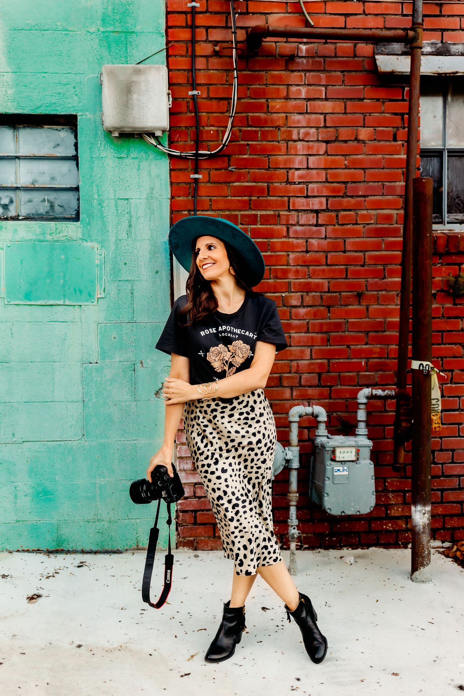 A portrait of Jette McCormick Photography standing with her legs crossed and holding her camera.