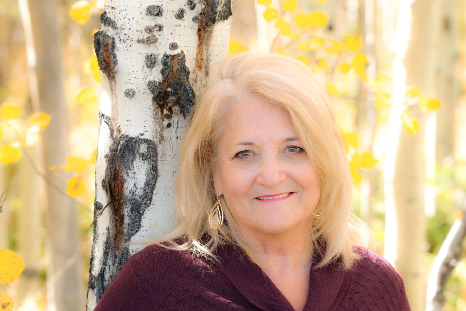 Close up portrait with autumn birch trees and golden leaves in background.