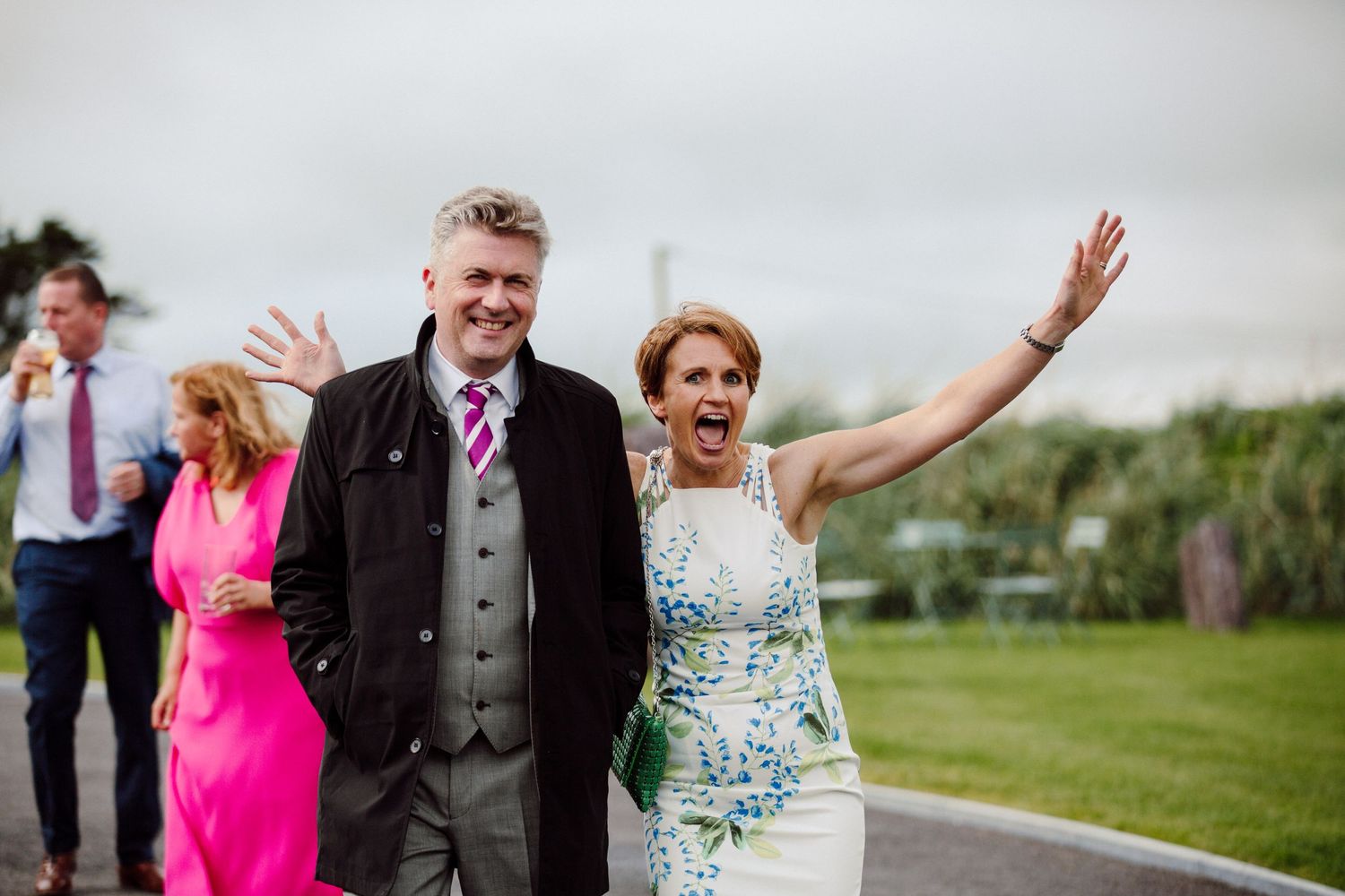 Wedding guests celebrate enthusiastically on a grassy path during the reception.