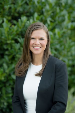 Professional portrait with green foliage background.
