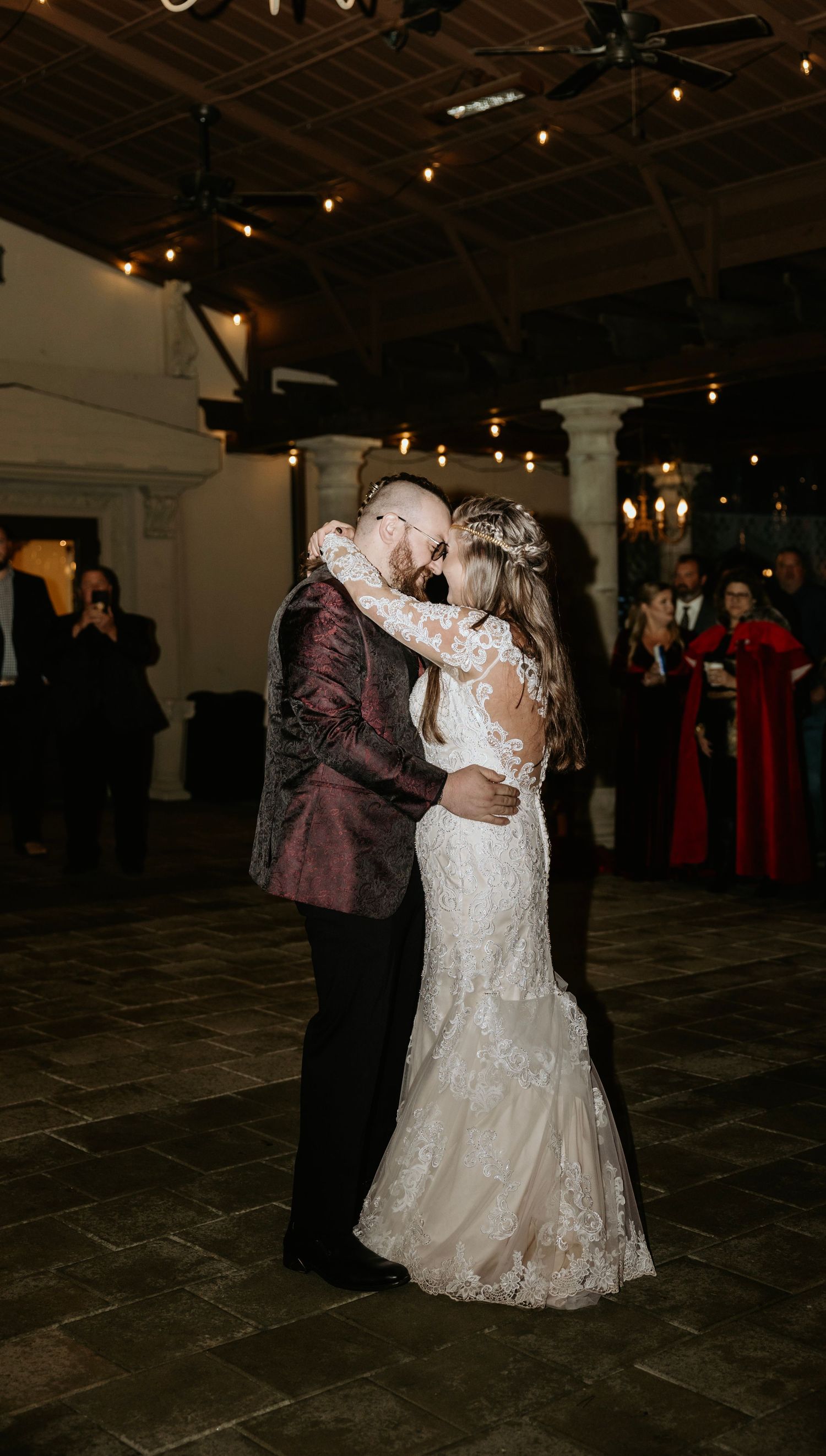 Couple sharing their first dance in an elegantly lit indoor venue with high ceilings.