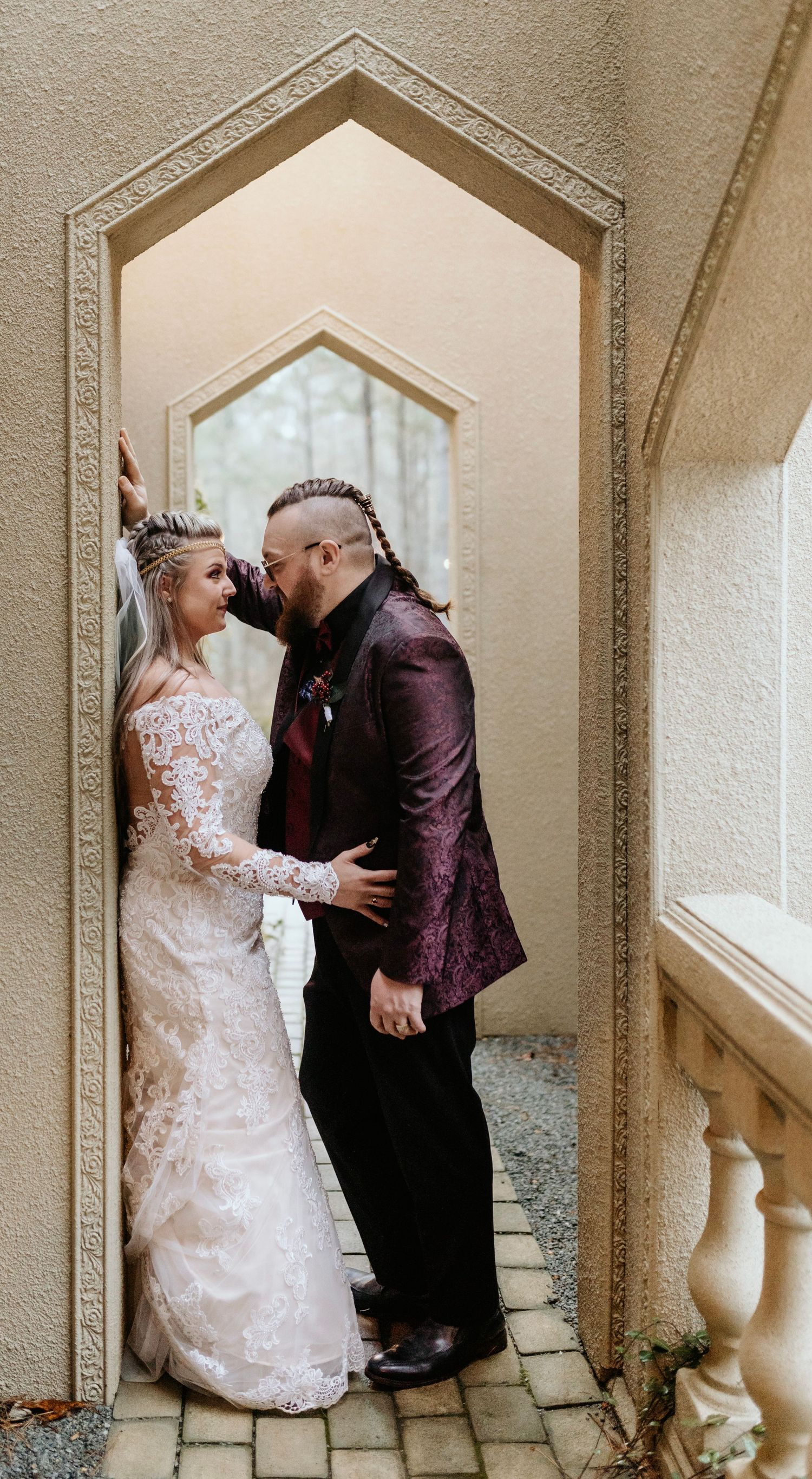 Romantic wedding portrait of couple in archway with ornate architectural details.