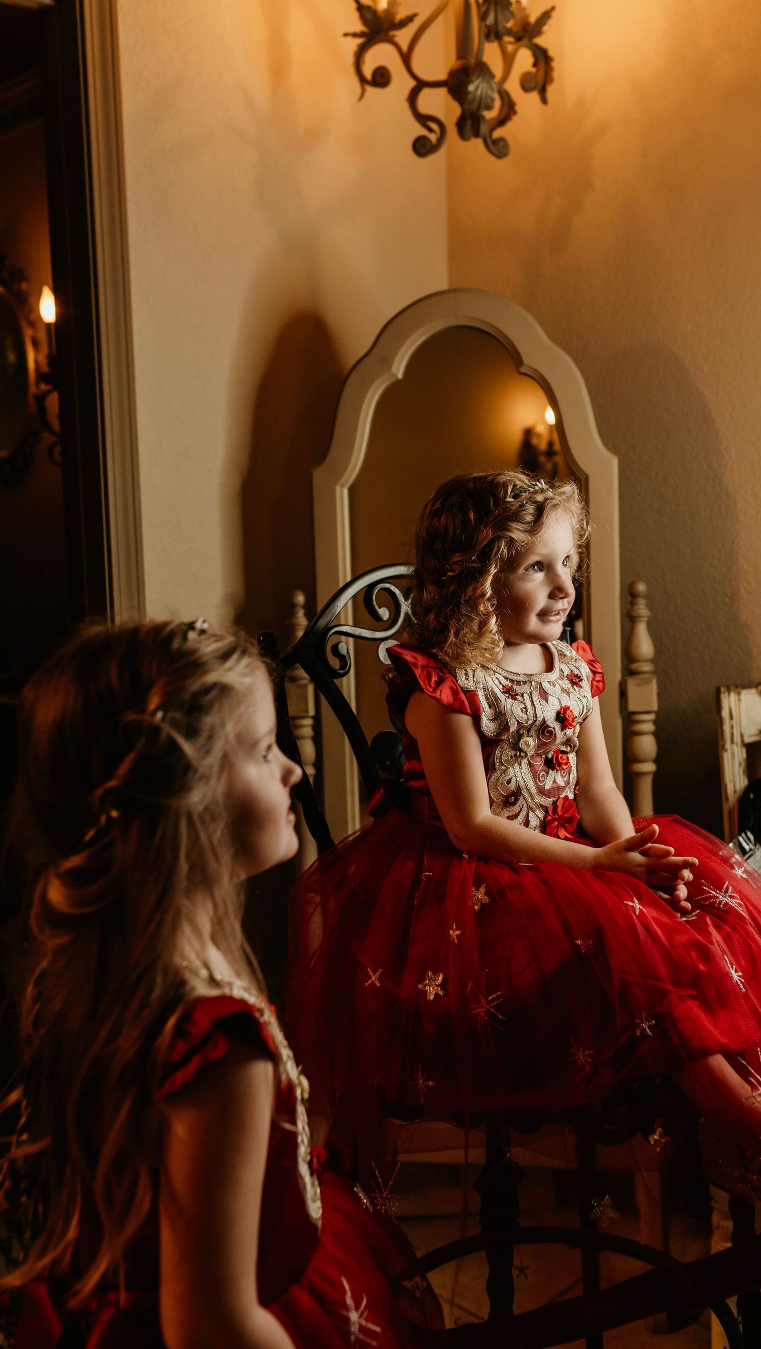 Two young attendees in matching red dresses sitting at elegant wedding venue.