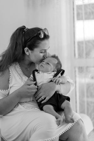 A tender moment between parent and baby in black and white photography.