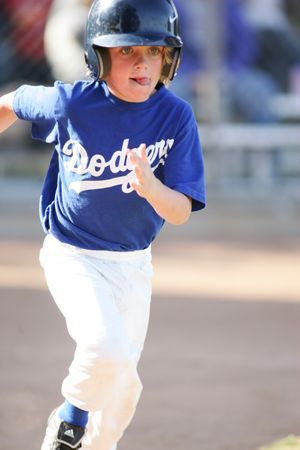 Young baseball player in Dodgers uniform runs on baseball diamond during game.
