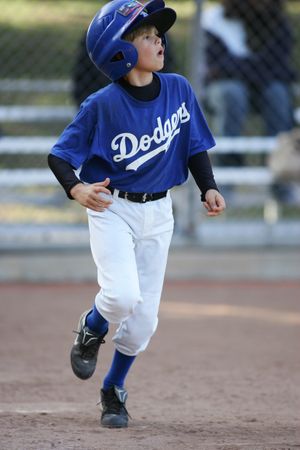 Young baseball player in Dodgers uniform runs on baseball diamond during game.