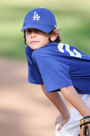 Youth baseball player in LA Dodgers uniform and cap looks over shoulder during game.