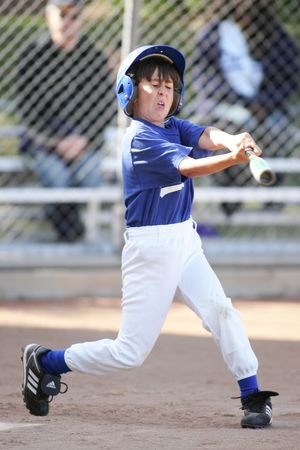 Youth baseball player in blue uniform swinging bat during game.