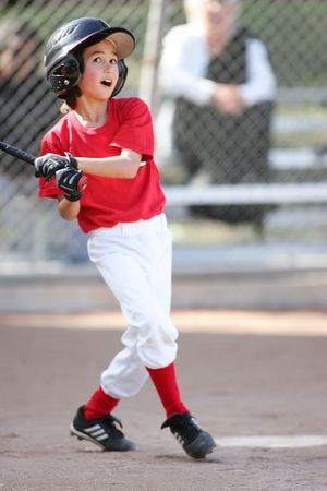 Youth baseball player in red uniform swinging bat during game.