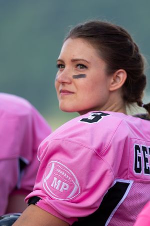 Player in pink football jersey with eye black markings looking to the side.
