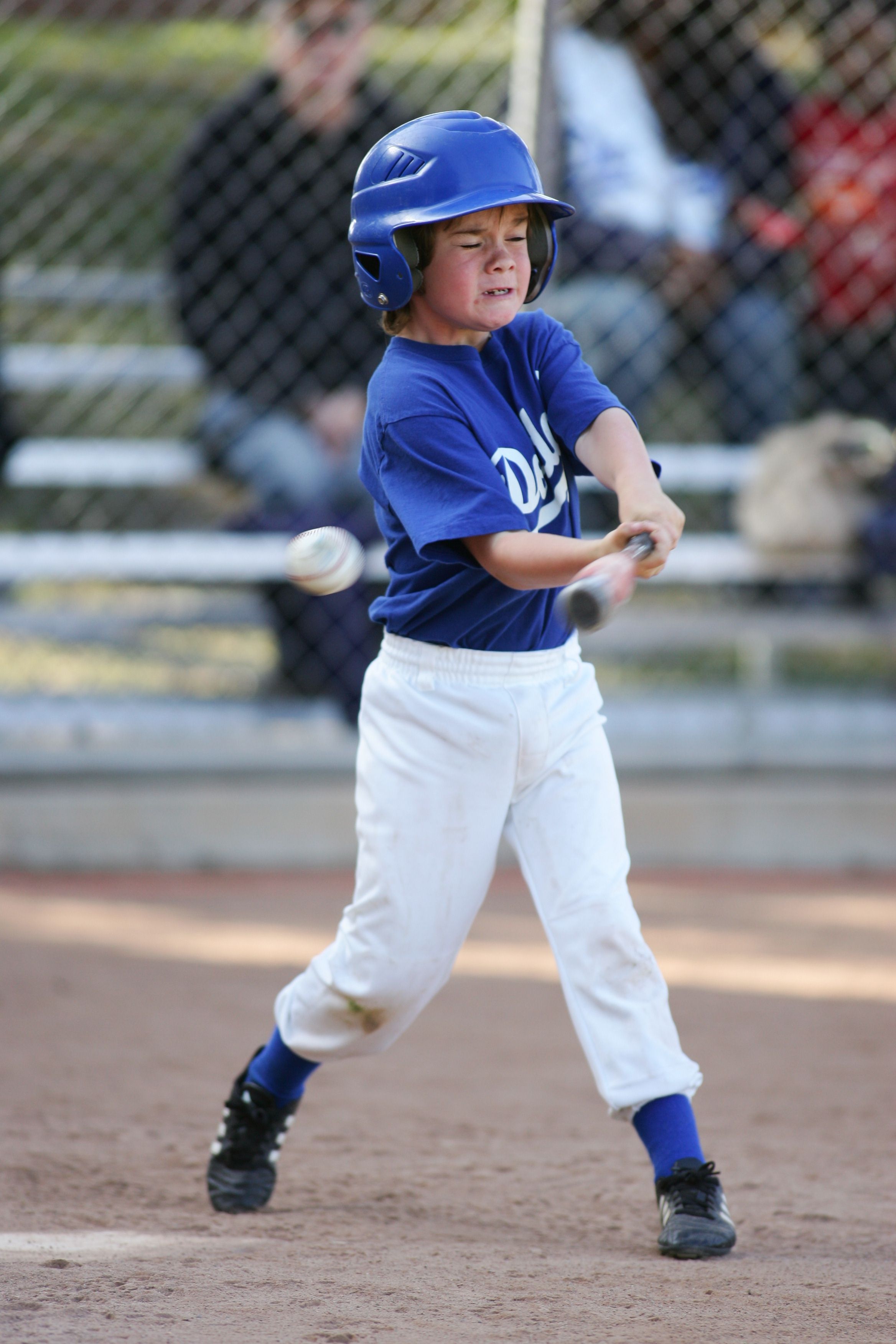Youth baseball player connects with pitch during Little League game.