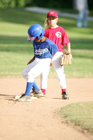 Two youth baseball players during game action on dirt infield.