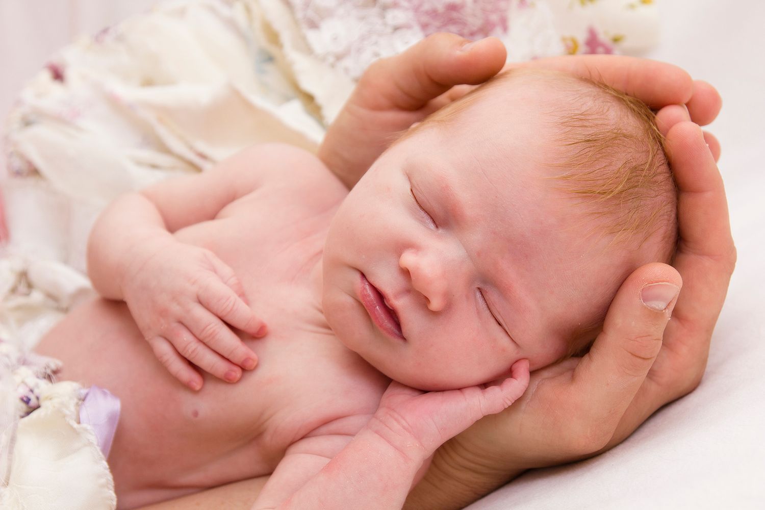 close up of a baby's face gently held in the parents hands