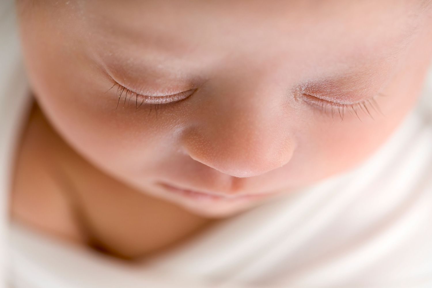 Dreamy macro shot of sleeping newborn's peaceful face.