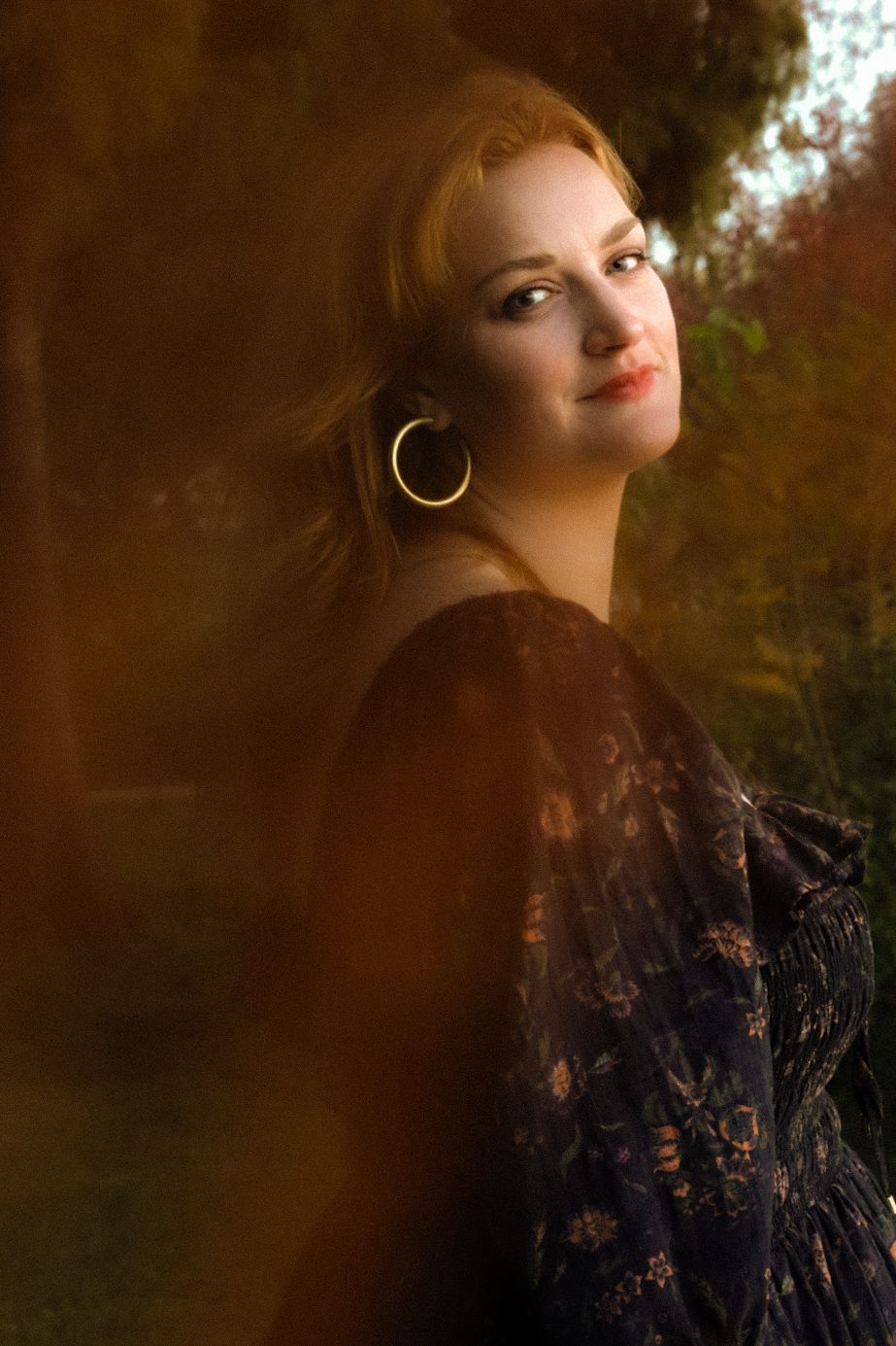 A woman looks at the camera with a shy smile with vintage hues.