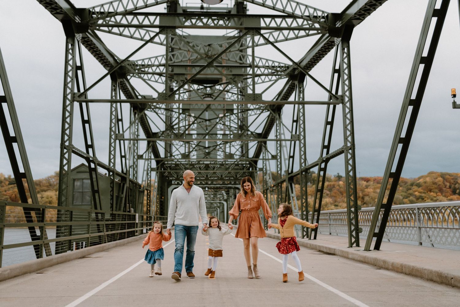 Family walking together on a steel bridge structure with geometric patterns.