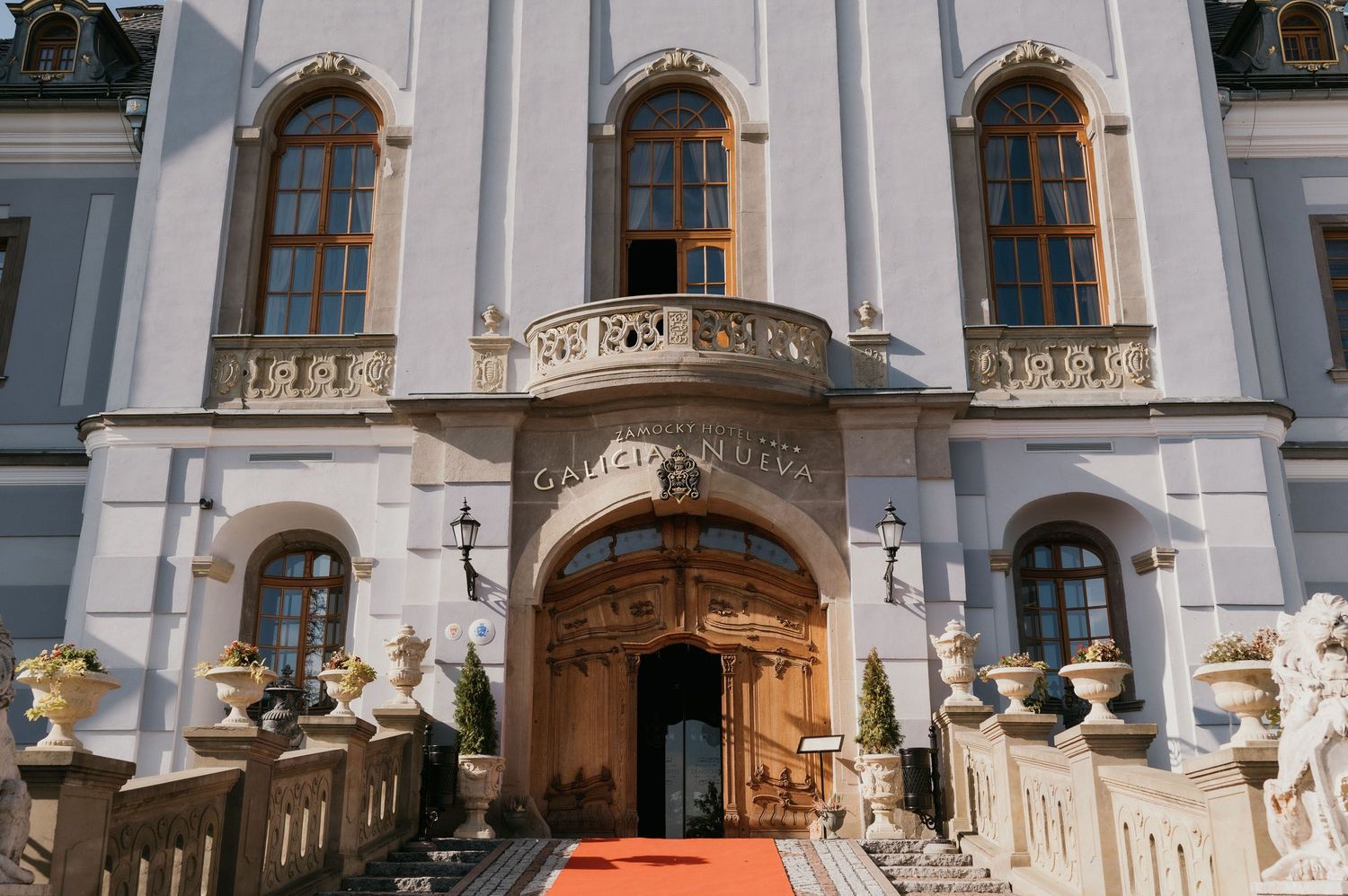 Elegant white palace facade with red carpet entrance and decorative statues.