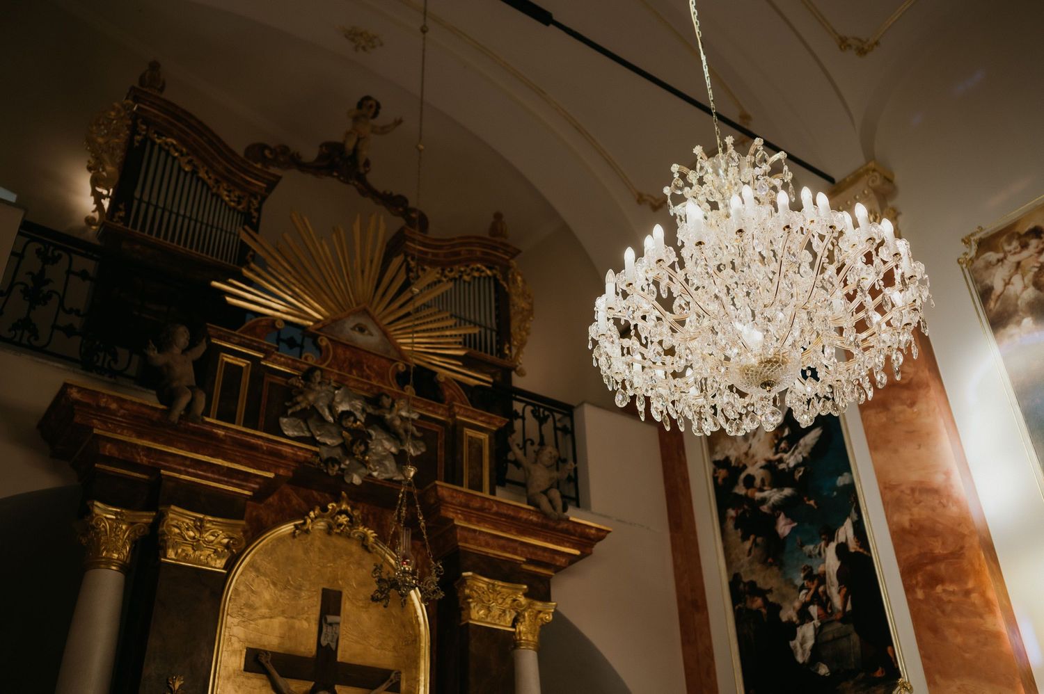 Ornate church interior with a grand crystal chandelier and baroque pipe organ.