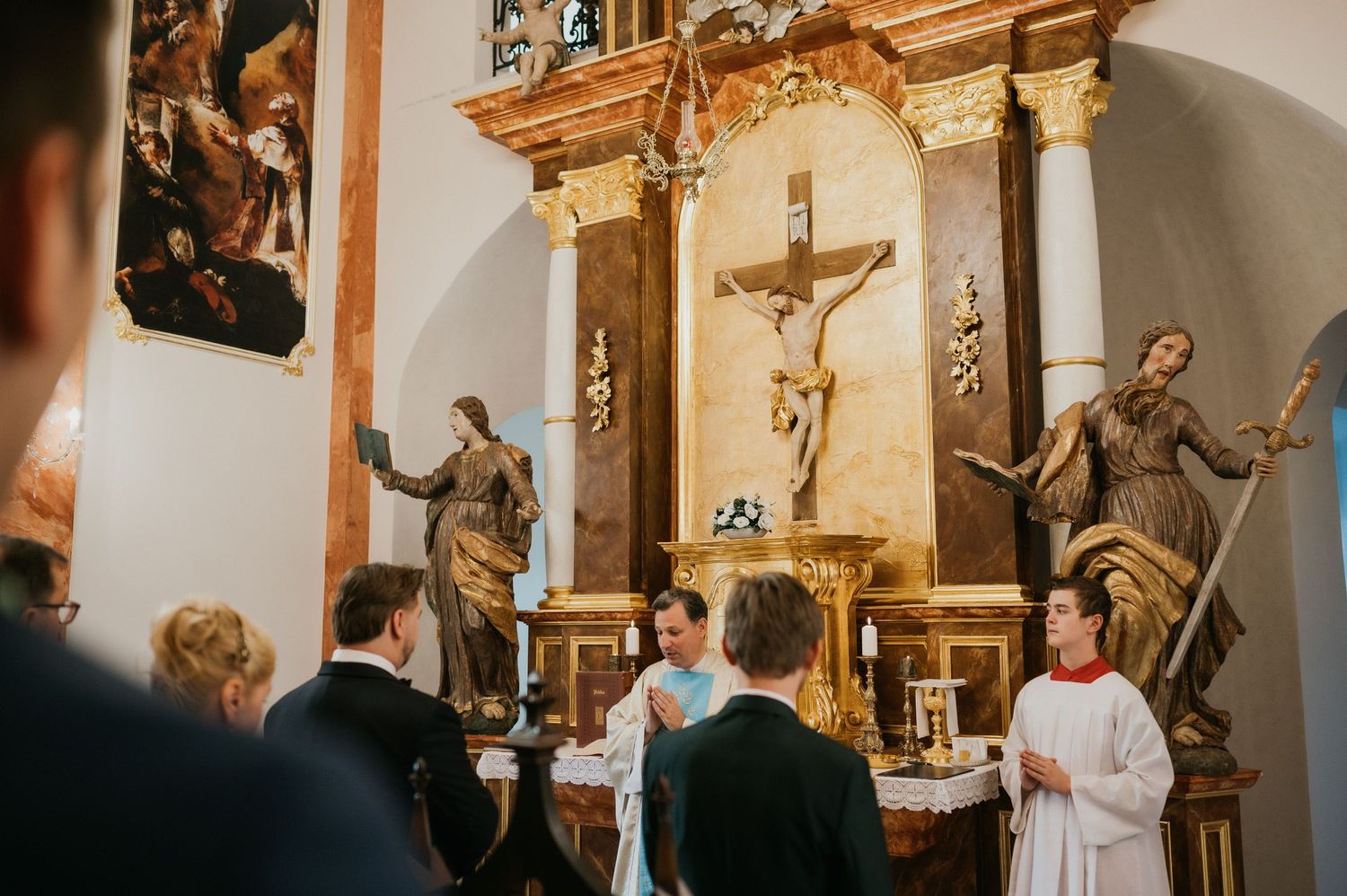 Church altar with ornate gold details and religious statues during wedding ceremony.
