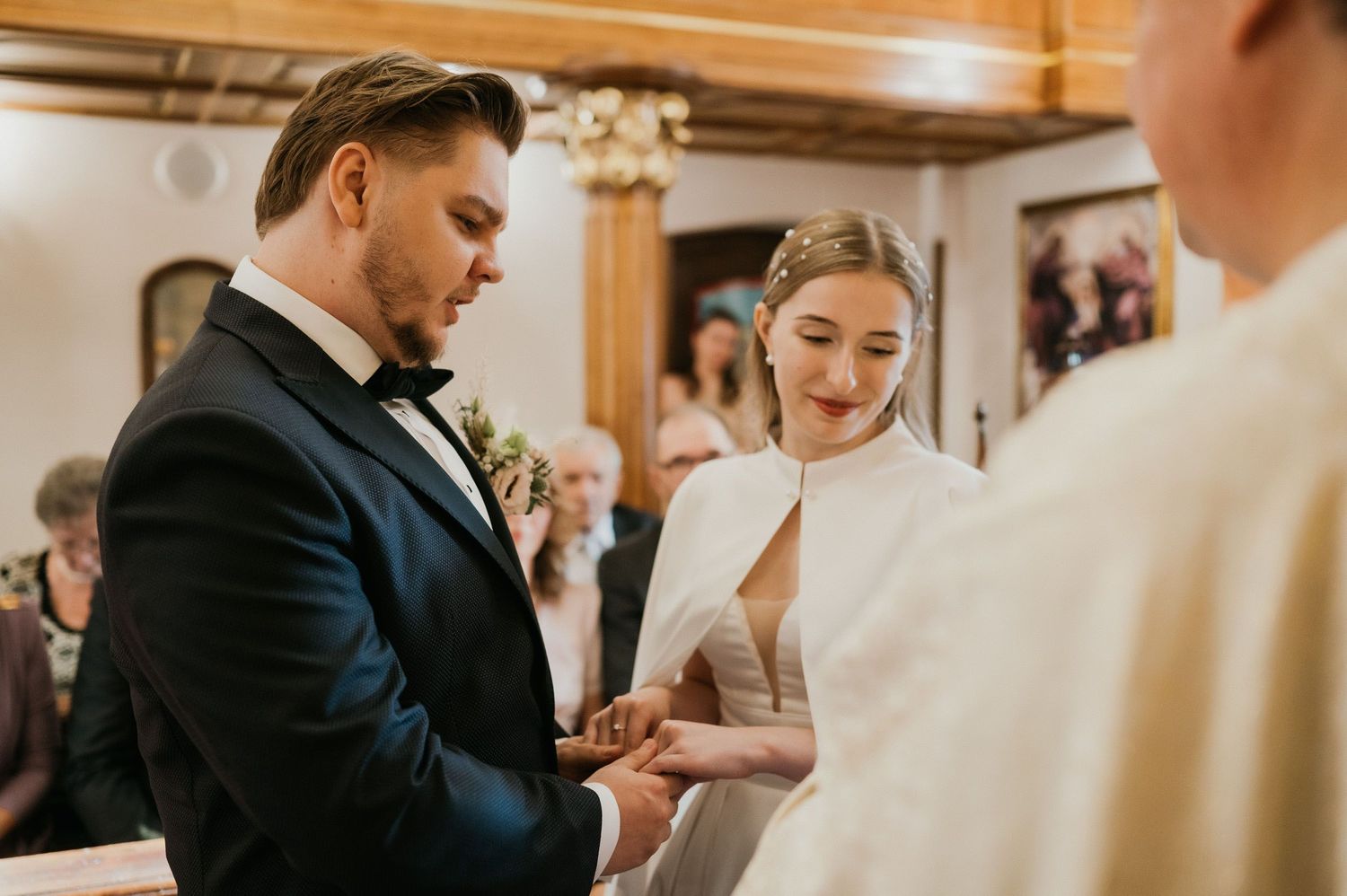 A couple exchanges rings during their wedding ceremony in an intimate church setting.
