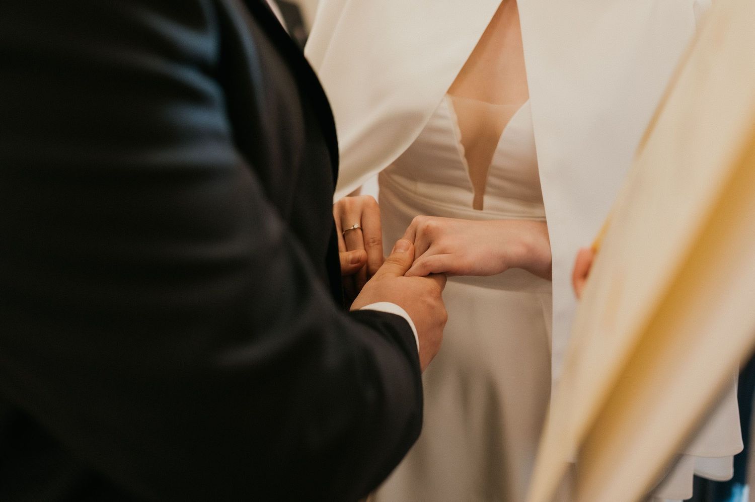 Close-up of hands exchanging wedding rings during a ceremony.