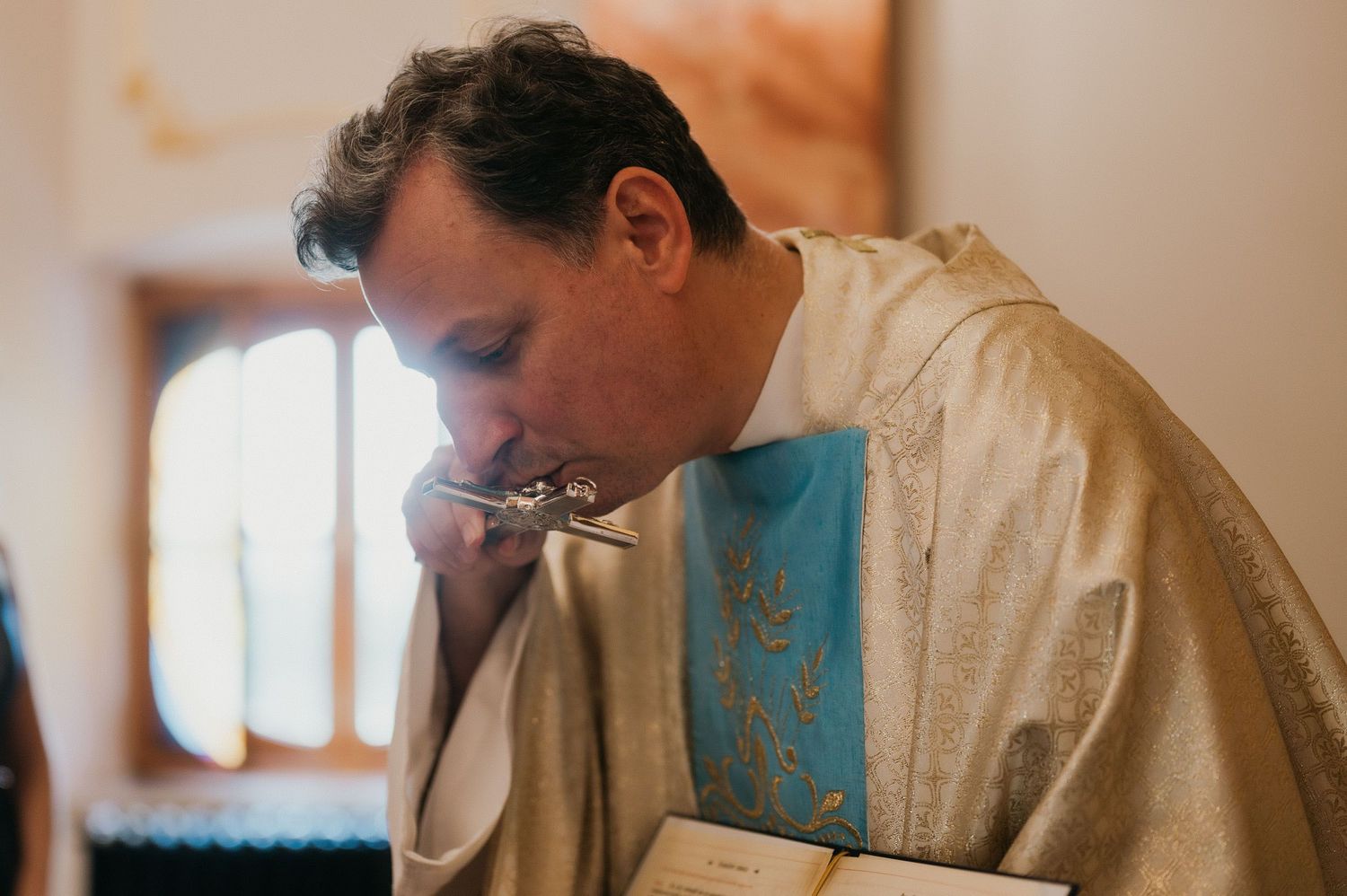 Priest in ceremonial robes bowing head during religious service.