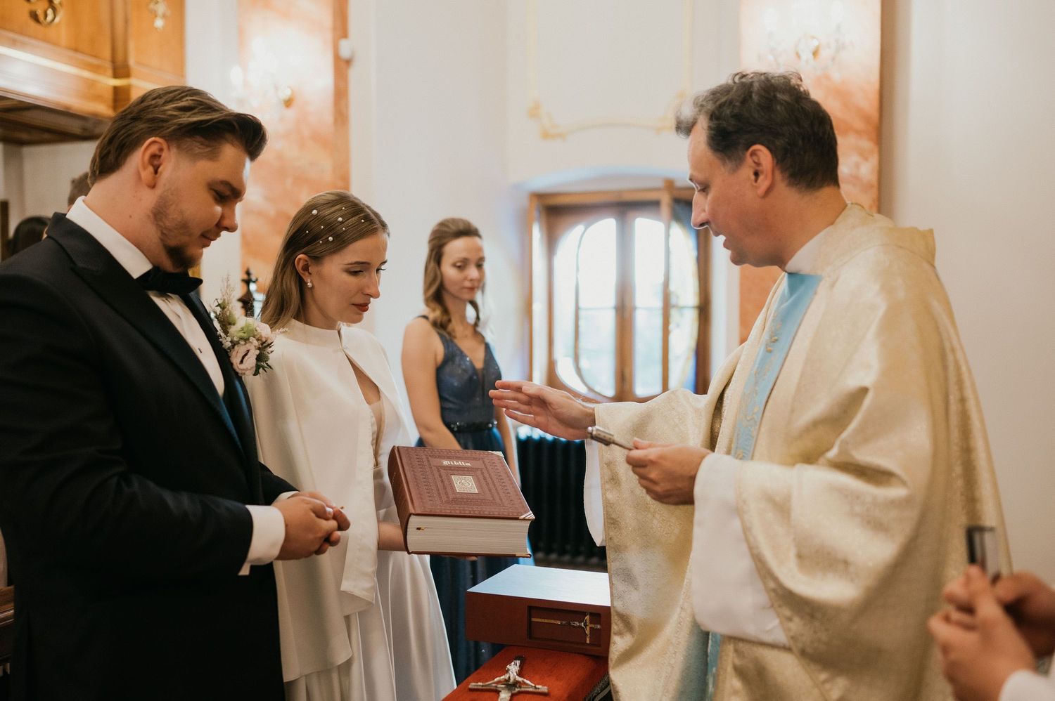 A wedding ceremony takes place in a traditional Catholic church setting.