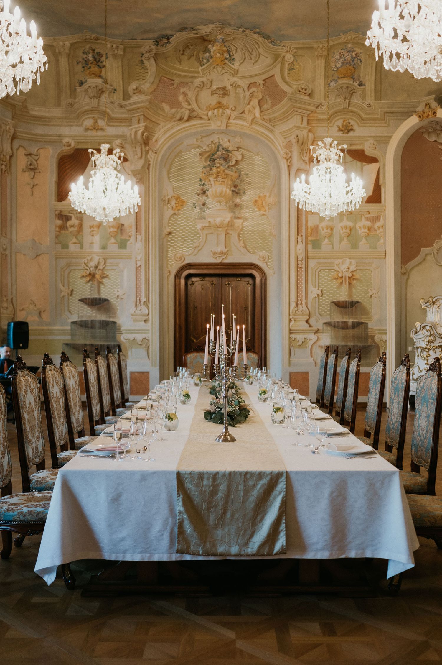 Elegant baroque dining room with crystal chandeliers and formal table setting for wedding reception.