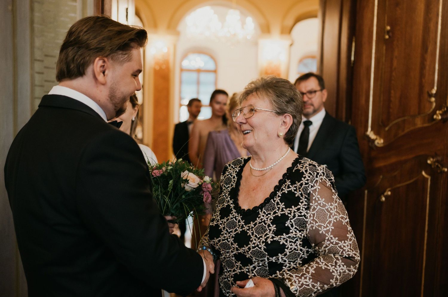 Guests sharing a warm moment at an elegant indoor wedding reception.