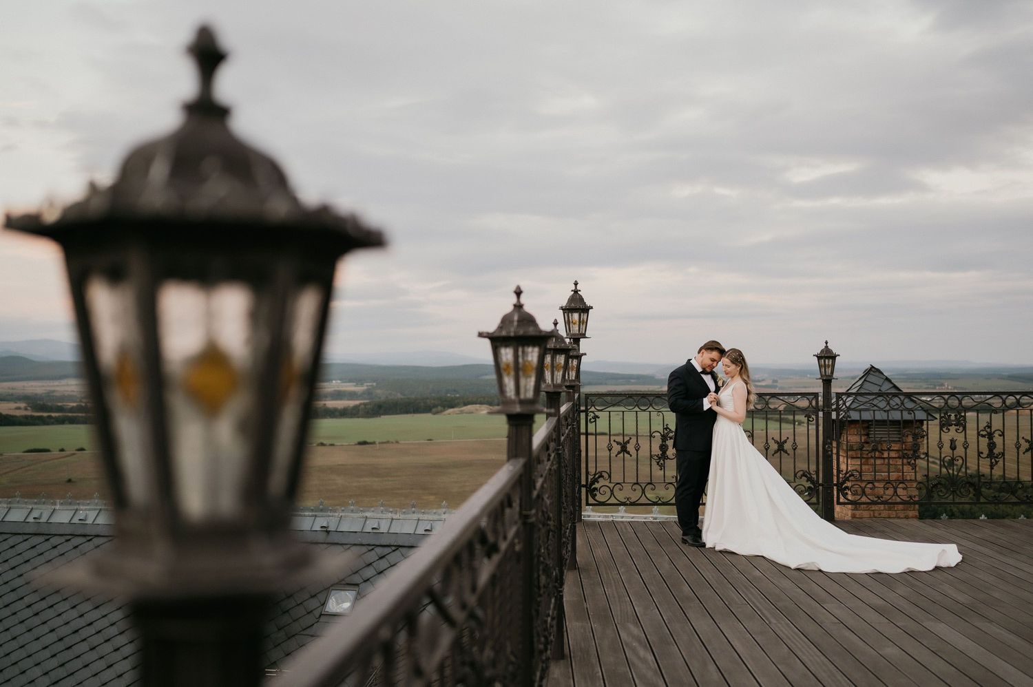 Wedding photography on wooden deck with antique lanterns and scenic mountain backdrop.