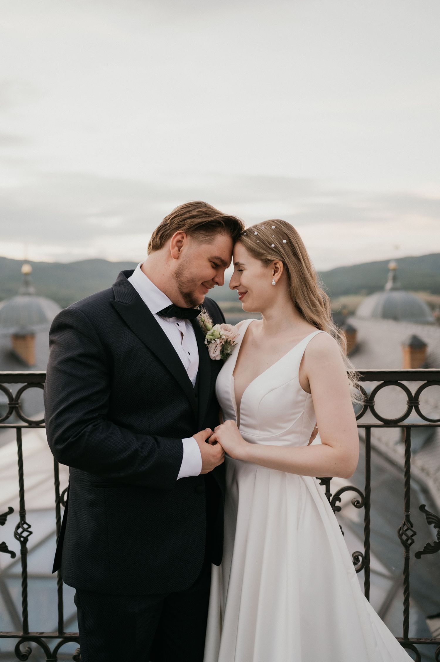 Intimate wedding moment captured on vintage-style balcony with mountain landscape.