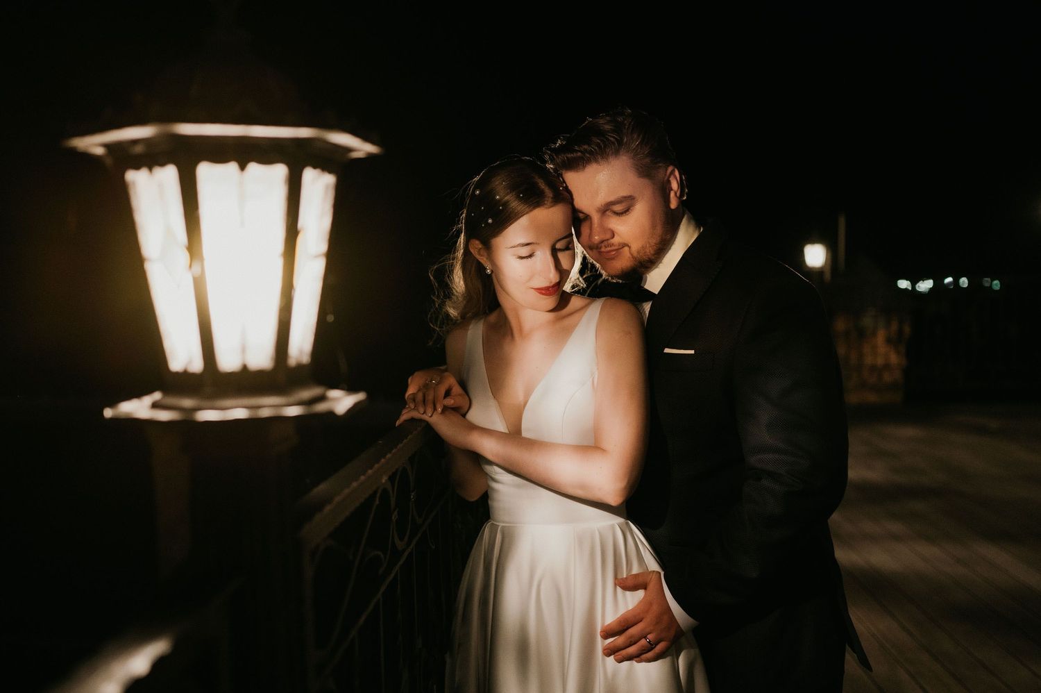 Intimate wedding couple moment captured under warm lantern light at night.