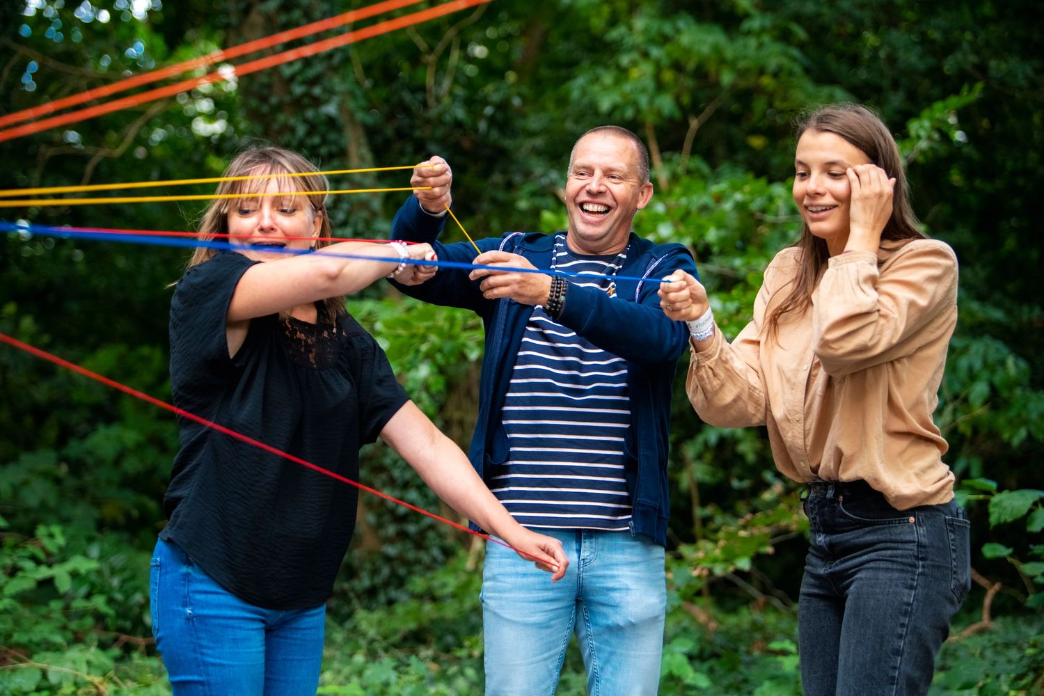 Friends playing with rubber bands and having fun in a garden setting.